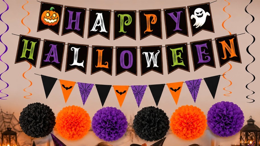 happy halloween banner, flags, and paper pom poms on a wall