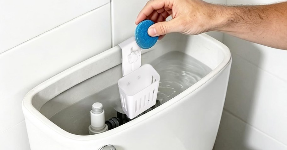 hand placing a blue cleaning tablet into a toilet tank holder