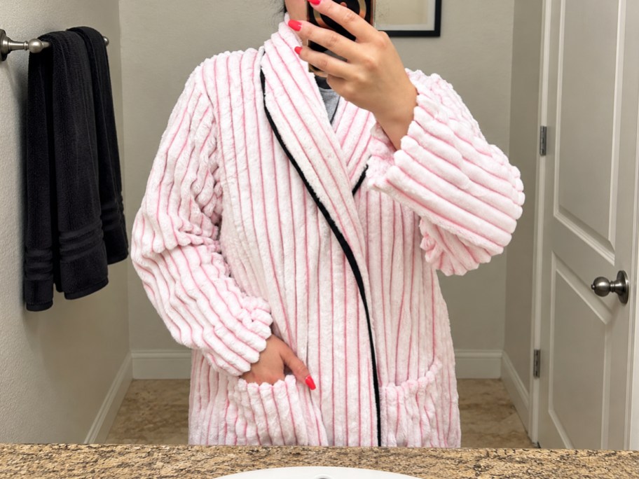 women taking photo in mirror wearing a pink striped bathrobe