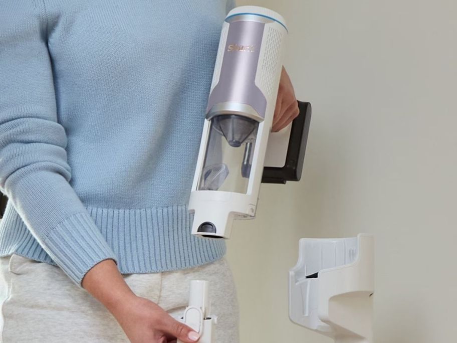 woman pulling apart the Shark vacuum while next to the stand