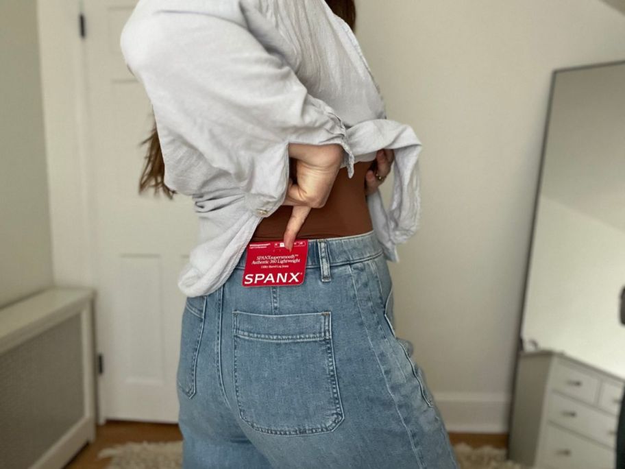 Woman pointing on tag on back of Spanx Jeans
