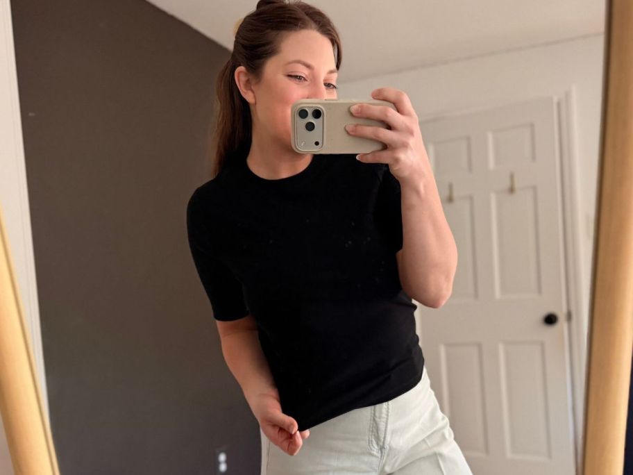 Woman taking a picture in a mirror while wearing a Spanx Tee