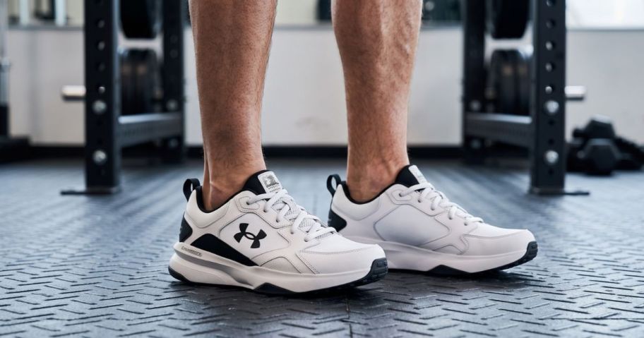 Man feet wearing Under Armour shoes with gym equipment in the background