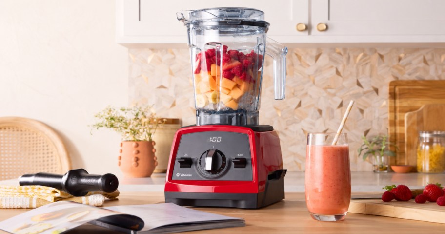 Red vitamix blender filled with frozen fruit and ice on kitchen countertop