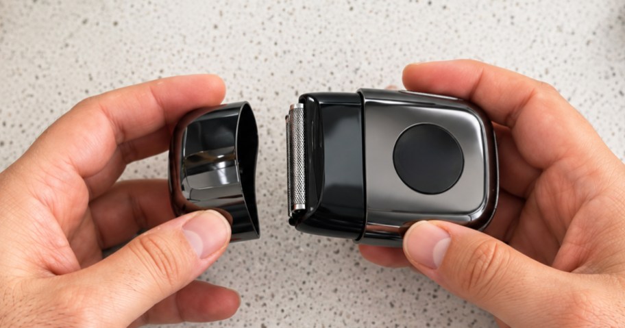 hand holding and taking the lid off a grey mini electric razor