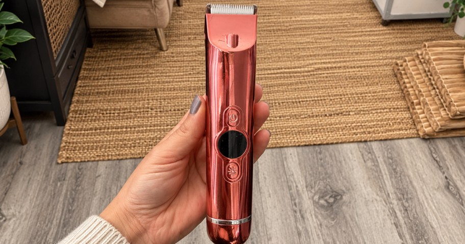 woman's hand holding up a metallic pink bikini trimmer