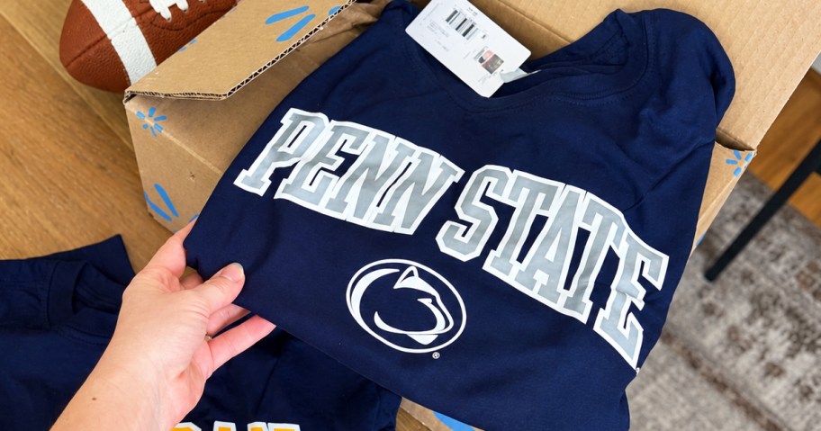 hand holding blue penn state tee on top of a walmart box