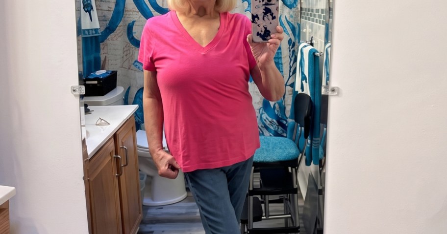 woman in a mirror wearing a tee inside a bathroom