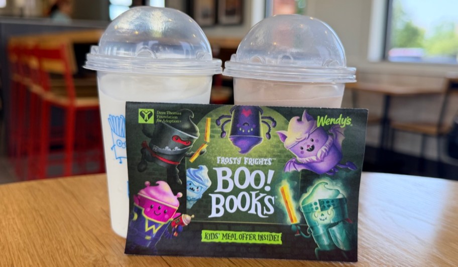 Two Wendy's frosty's with a book book coupon book sitting infront of them.