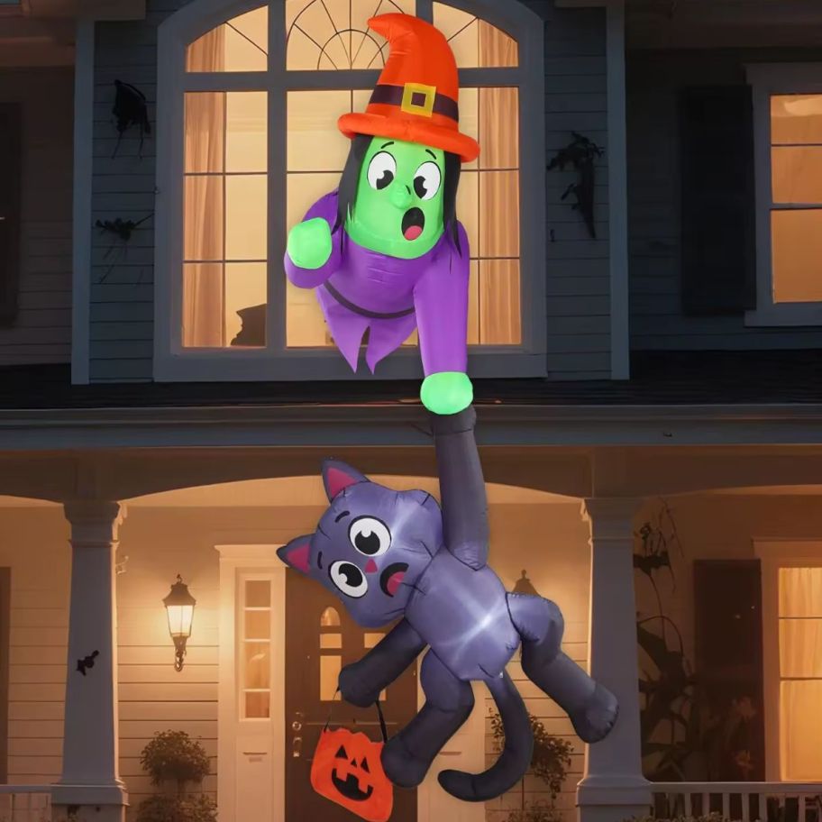 Witch and cat halloween decor outside of an upstairs window