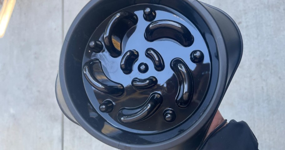 A black plastic slow feeder dog bowl with a maze-like pattern of raised ridges.