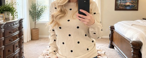 woman taking photo in mirror wearing a polka dot print sweater