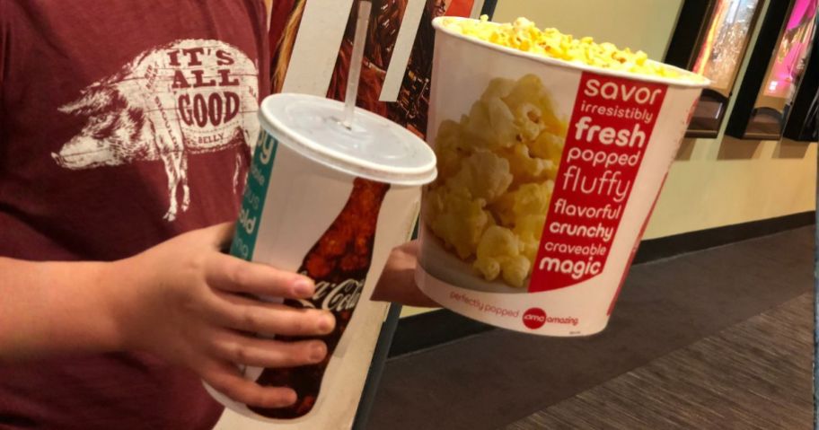 person holding amc drink and popcorn