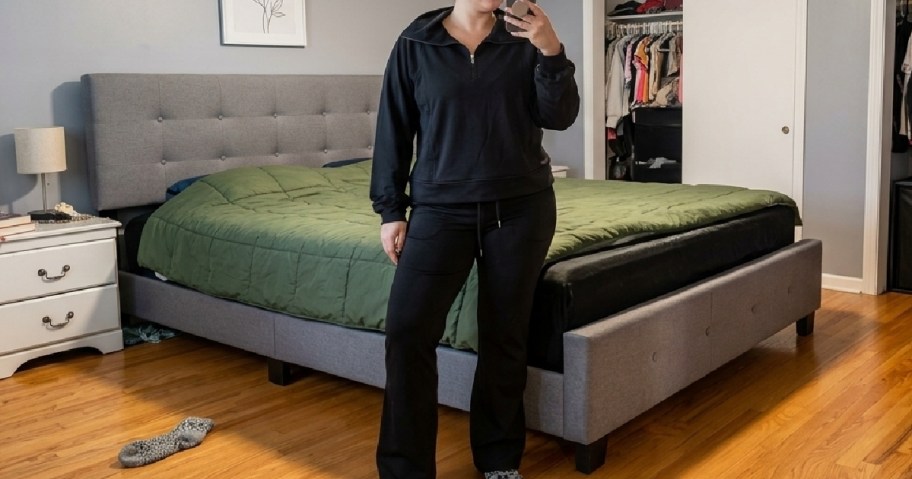 woman standing in bedroom wearing a black sweatsuit