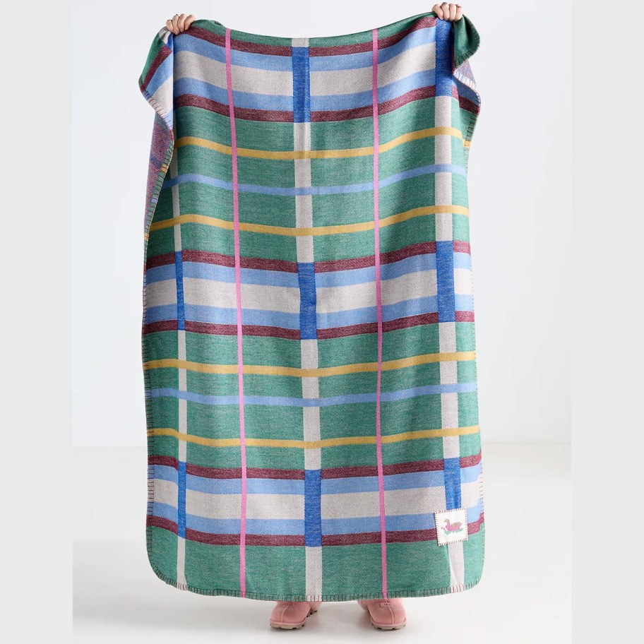 person holding up green and blue blanket plaid