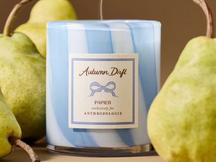 a blue glass jar candle next to pears