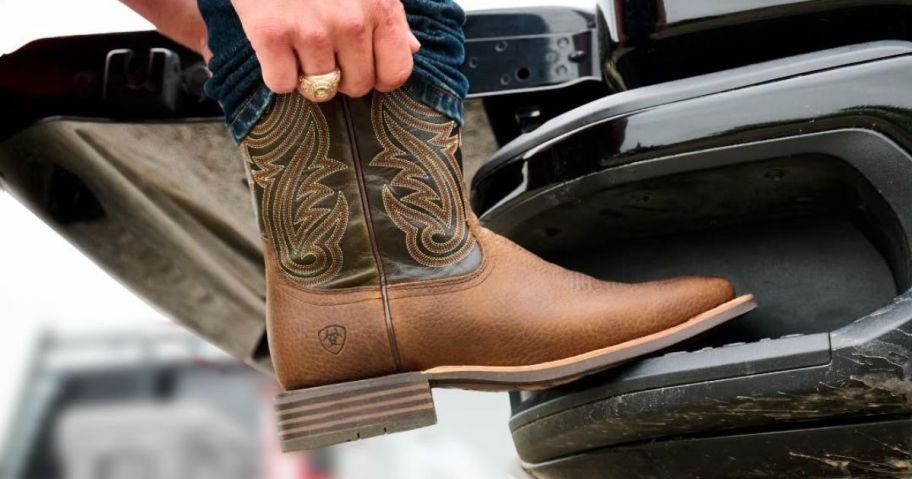 man putting on Ariat boot on truck