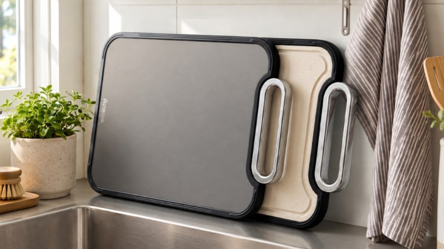 two cutting board leaned against a backsplash by a sink