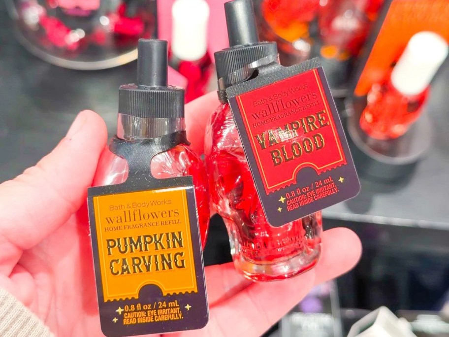 a hand holding two scent refills