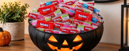 packs of Twizzlers candy in a black jack-o-lantern bowl