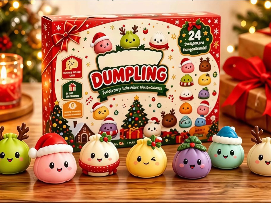 A red Christmas dumpling advent calendar box surrounded by festive, cute dumpling figurines wearing holiday hats and antlers on a wooden surface.