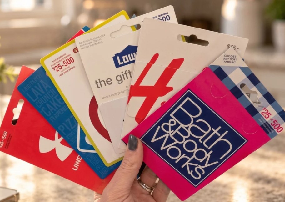 a hand holding fanned out gift cards from popular retailers