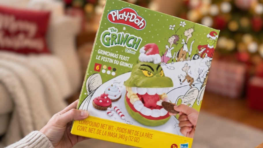 a hand holding a box with a grinch playdoh set