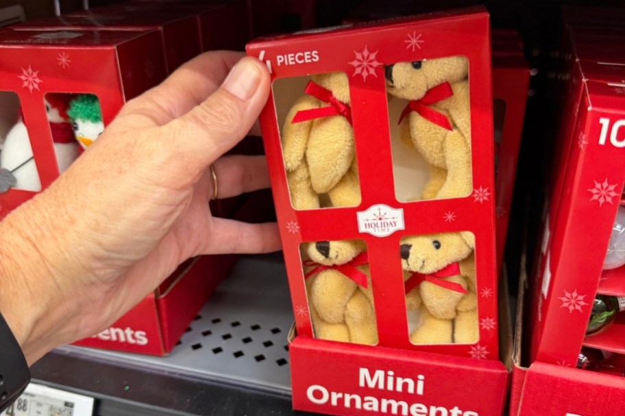 a hand reaching for a 4-pack of mini bear ornaments