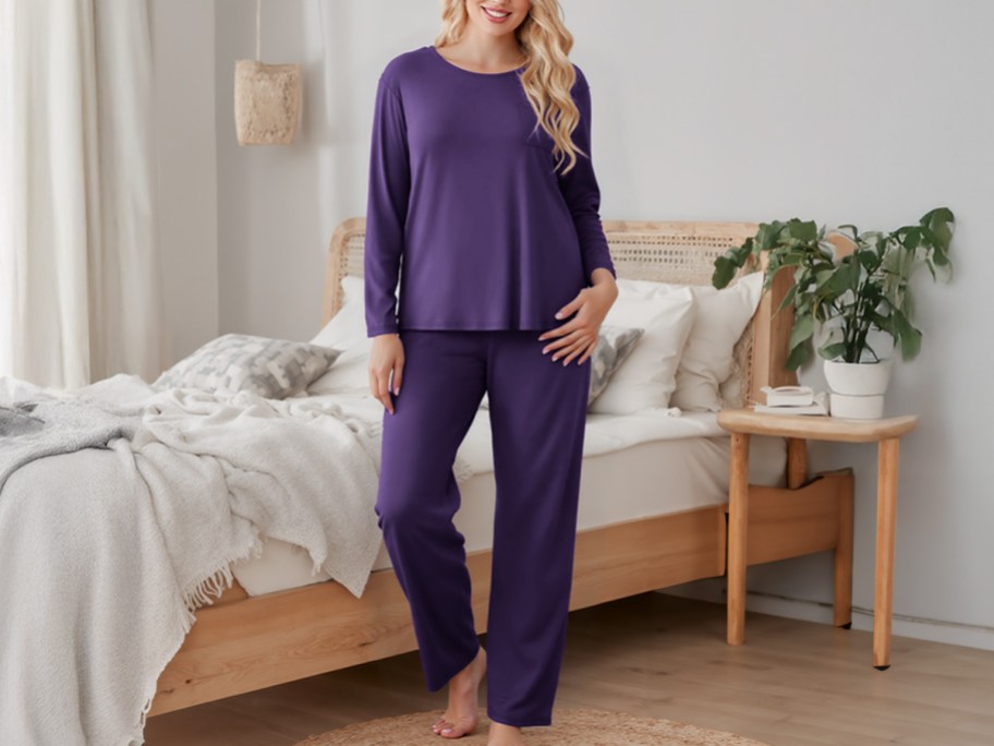 woman wearing long sleeve purple pajamas in front of a bed
