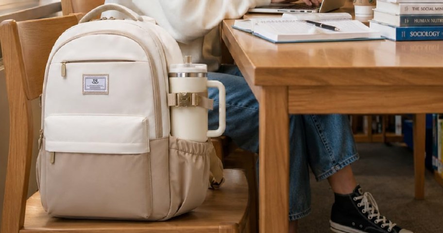 cream backpack with a student sitting at a desk