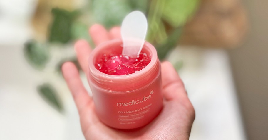 hand holding up a pink jar of medicube Jelly Cream