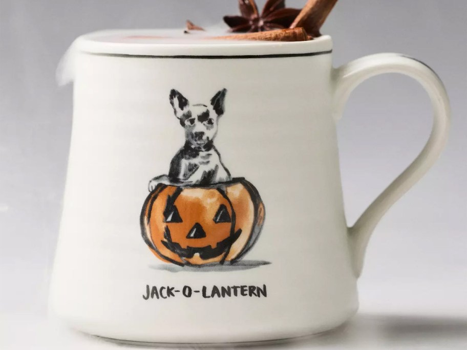 white dog with pumpkin mug on table