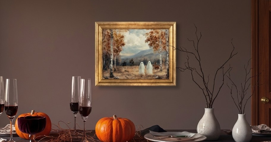framed picture of ghosts on wall above table with wine glasses and pumpkins