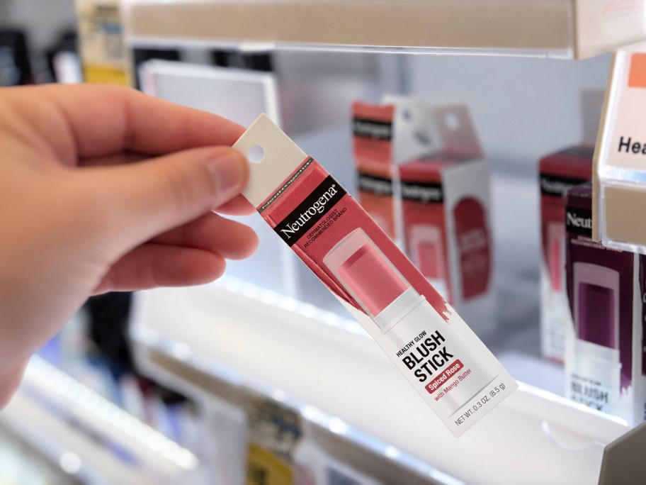 hand tipping a makeup item away from the shelf in a store