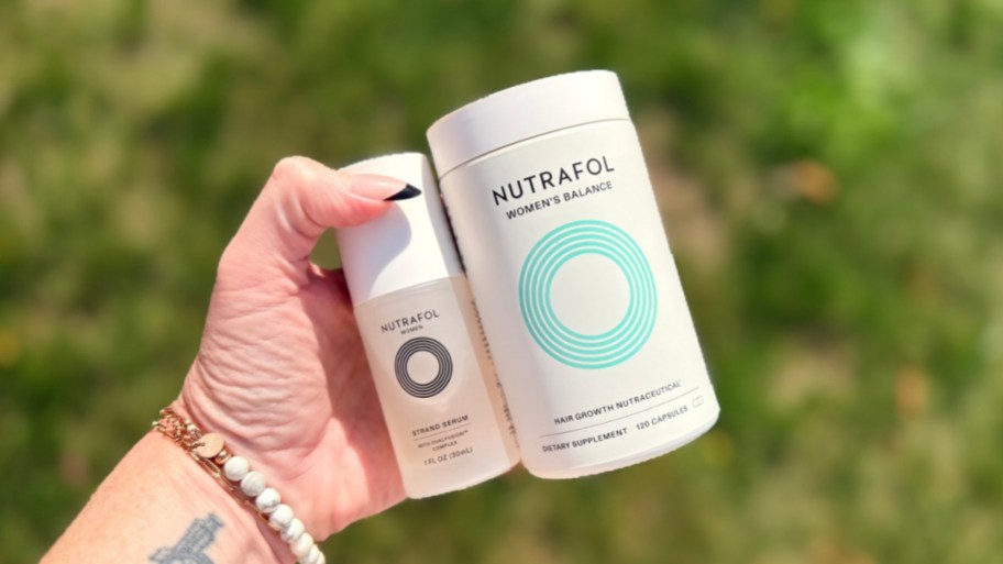 a hand holding a bottle of hair serum and hair supplements