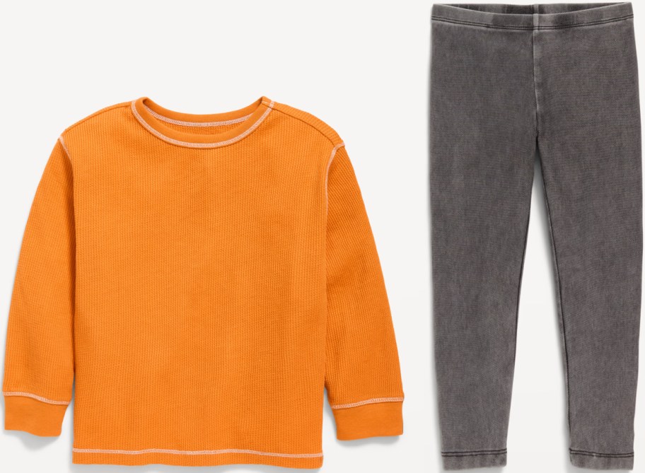 An orange long-sleeve waffle-knit crewneck shirt paired with gray mineral-wash leggings.