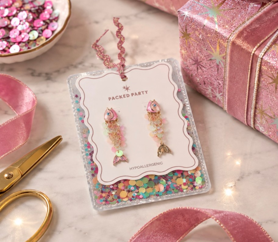 fish sparkle earrings on table with pink wrapping 