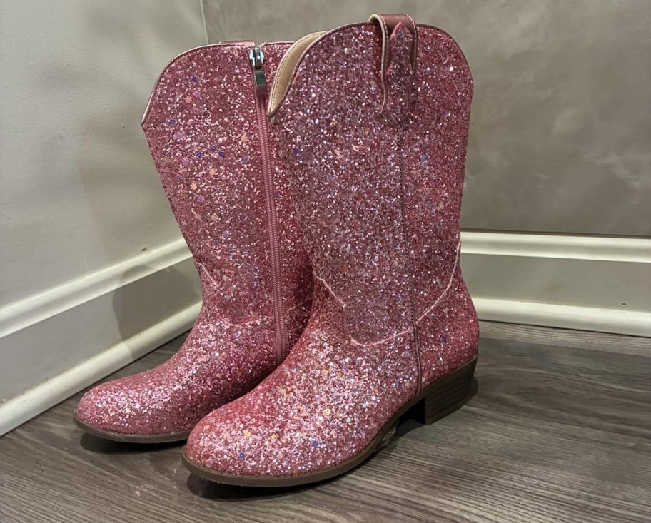 pair of pink glitter cowgirl boots on wood floor