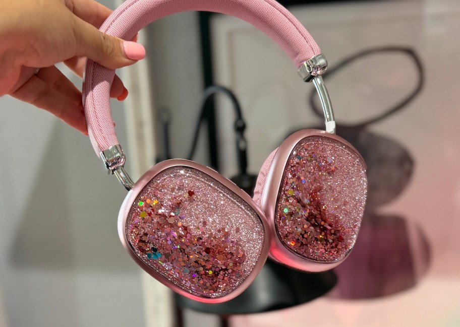 hand holding pair of pink glitter headphones