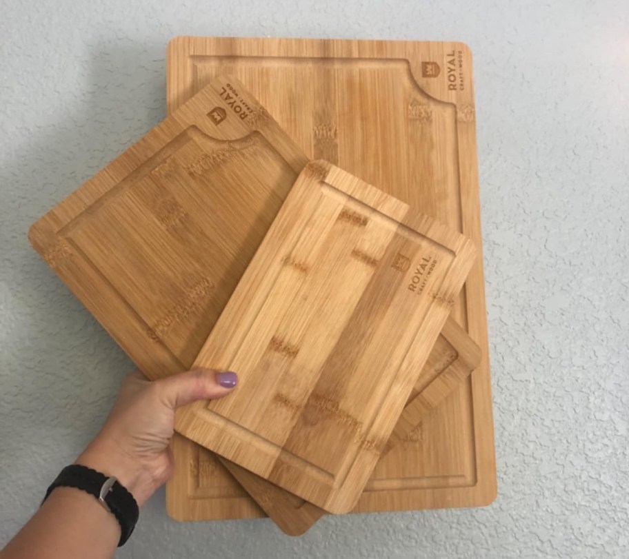 hand holding three bamboo cutting boards