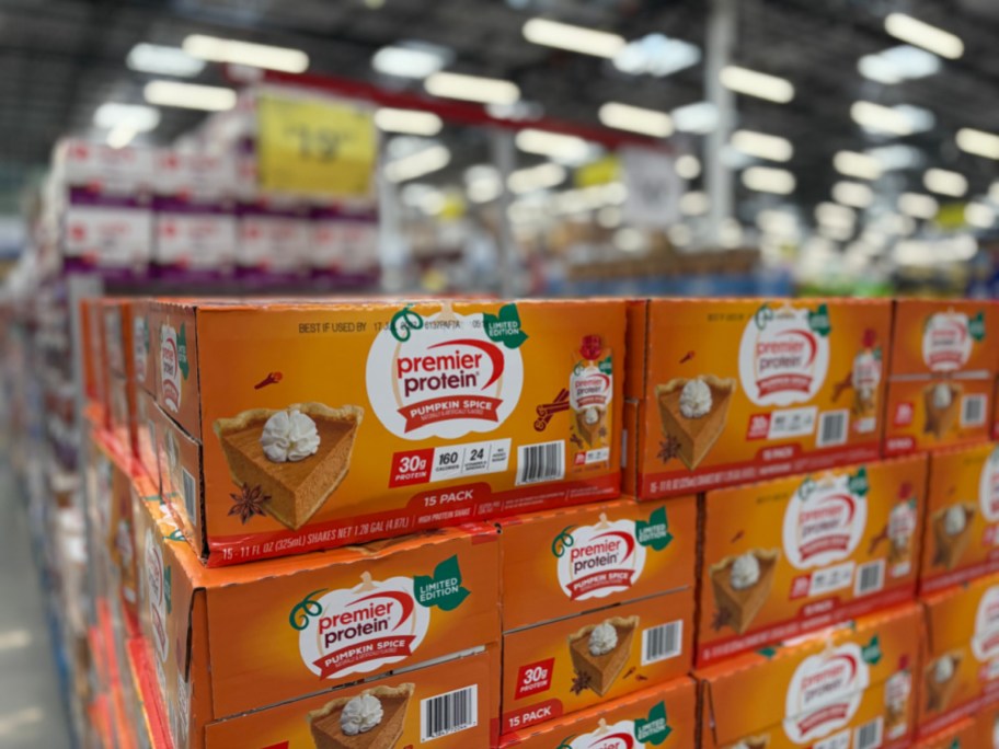 Stacked 15-pack cases of Premier Protein Pumpkin Spice shakes displayed on a store shelf.