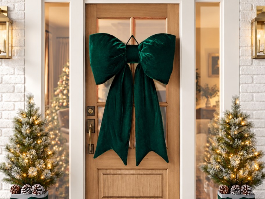 a green velvet oversized bow handing on a front door