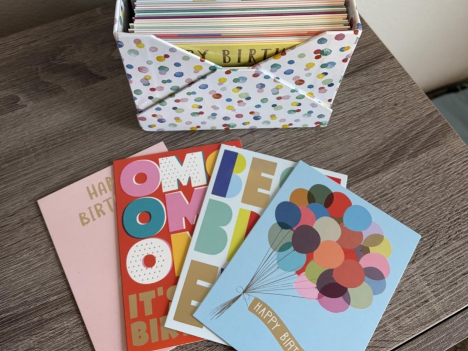 box of birthday cards next to 4 cards on a table