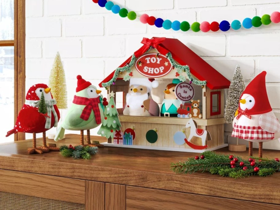 3 fabric birds next to a small Christmas toy shop display