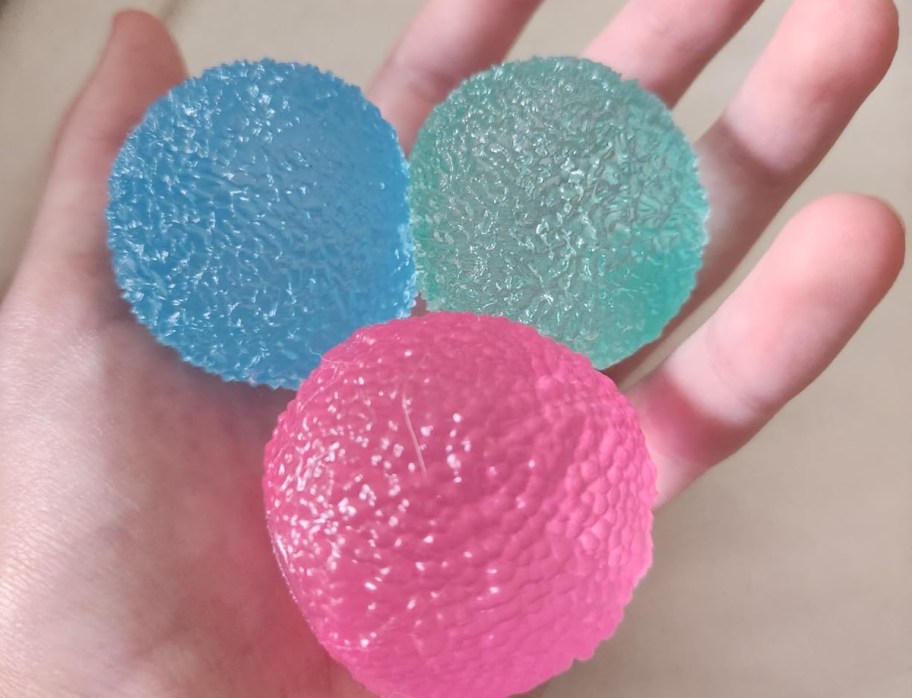 hand holding blue green and pink textured ball squishies