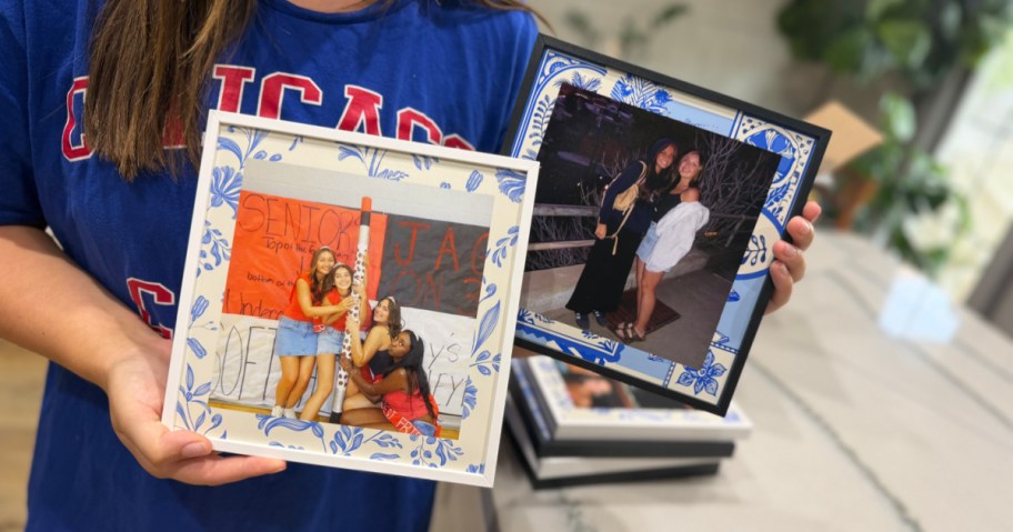 A person holding two custom photo frames with blue and white patterned borders displaying pictures of friends.