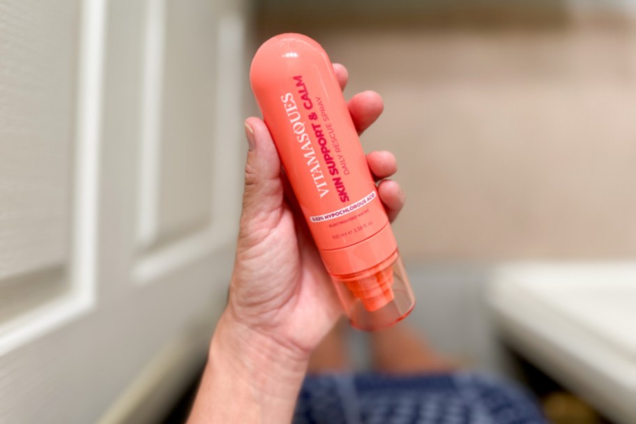 hand holding orange spray bottle