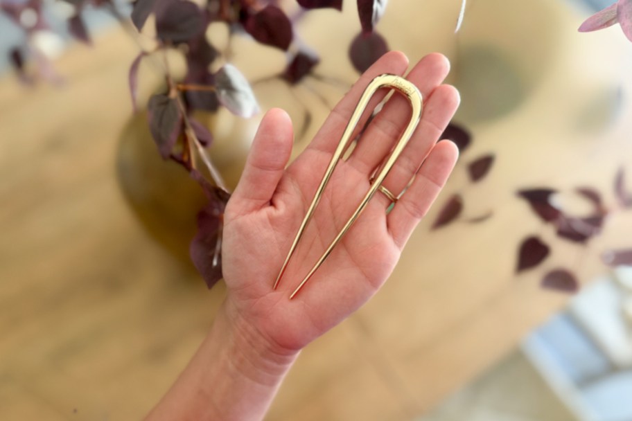 hand holding gold u shaped hair pin