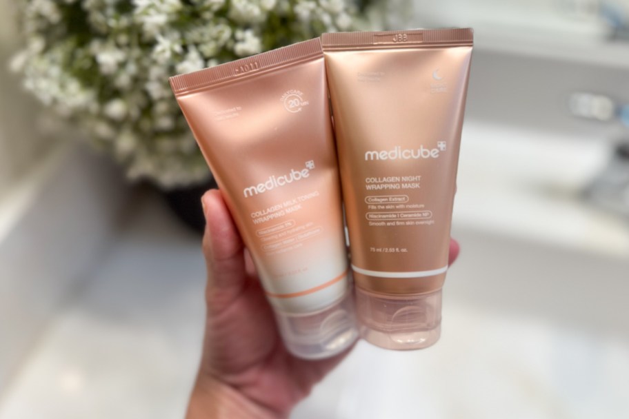 hand holding two pink face wash tubes