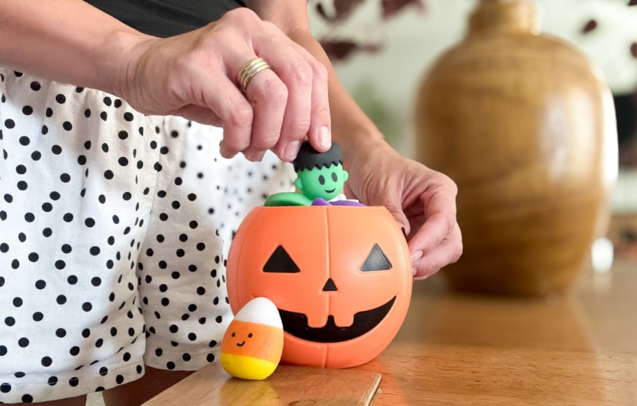 hand pulling a squishy Frankenstein toy out of a halloween pail 